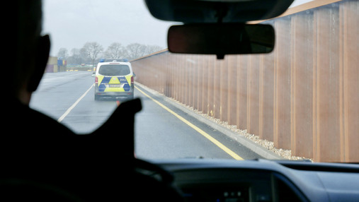 Foto zum Thema „Zoll Hamburger Hafen“: Zu sehen ist, wie Felix den Streifenwagen steuert. Es ist nur sein Umriss zu erkennen.