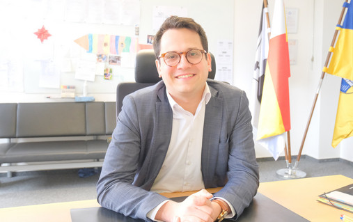 Zu sehen ist ein Foto von Benjamin Fadavian. Er sitzt am Schreibtisch.