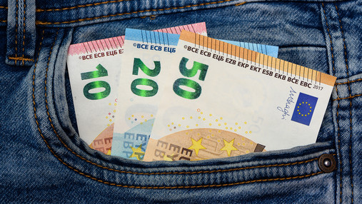 Das Foto zeigt Geldscheine, die aus der Hosentasche einer Jeans herausschauen.