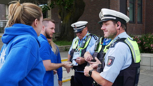 Foto zum Thema "Polizei Einsatzversorgung": Zu sehen ist Svenja, wie sie Patches an eine Gruppe Polizist*innen verteilt.