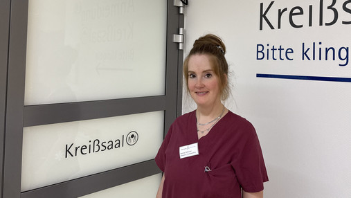 Foto zum Thema "Wie wird man Hebamme": Zu sehen ist Annina, die in Frankfurt am Main als Hebamme arbeitet. Sie steht vor der Tür zum Kreißsaal.