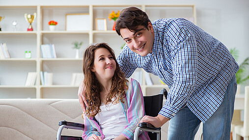 Foto zum Thema "Ausbildung bei der Sozialversicherung": Zu sehen ist ein junges Paar. Sie sitzt im Rollstuhl, er kümmert sich.