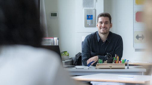 Symbolfoto zum Thema "Lehrkräftebildung": Zu sehen ist ein junger Lehrer, der am Pult sitzt.