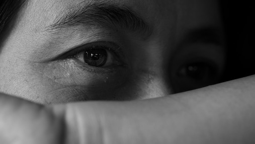 Foto zum Thema Gewalt am Arbeitsplatz: Zu sehen ist eine Frau, die schützend den Arm vor ihr Gesicht hält.