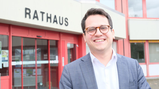Zu sehen ist ein Foto von Benjamin Fadavian, Bürgermeister von Herzogenrath. Er steht vor dem Rathaus.