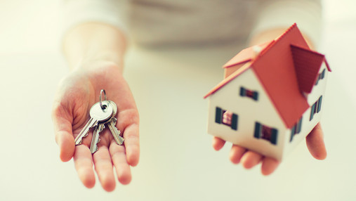 Foto zum Thema "immobilienfinanzierung dbb vorsorgewerk": Zu sehen sind zwei Hände. Die linke hält Haustürschlüssel, die rechte ein Modellhaus.