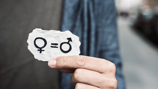 Foto zum Thema Gendermedizin und Gender-Budgeting: Zu sehen ist eine Hand, sie hält einen Papierschnipsel auf dem die Symbole für Mann und Frau stehen, verbunden durch ein Gleichheitszeichen.