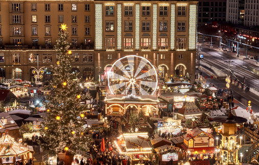 Foto zum Thema "Dresdener Striezelmarkt": Zu sehen ist eine Luftaufnahme des Marktes, die Lichter leuchten in der Dunkelheit. In der Mitte ist das Riesenrad zu sehen. 