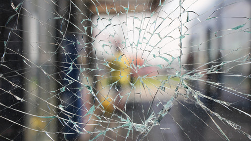 Foto zum Thema "Gewalt gegen Beschäftigte im öffentlichen Dienst": Zu sehen ist eine zersprungene Scheibe.